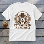 White t-shirt with brown graphic of a lantern and text "Established in the Hills."