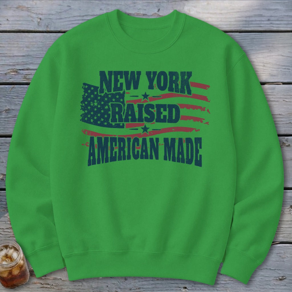 Green crewneck sweatshirt featuring distressed patriotic graphic with text reading New York Raised American Made.