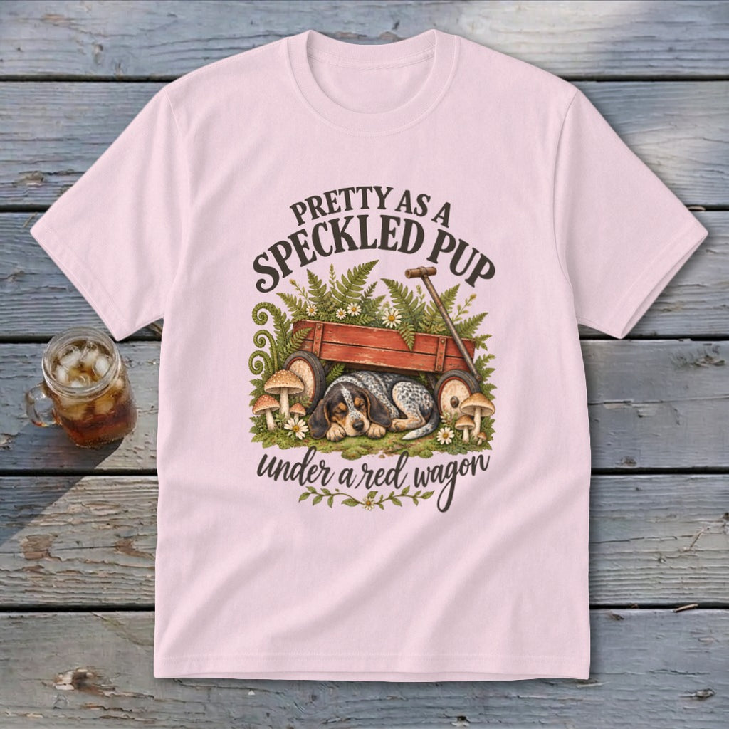 Pink t-shirt with a speckled pup sleeping under a red wagon, with text.