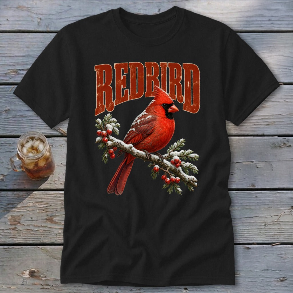 A black t-shirt features a graphic of a red cardinal perched on a snow-covered pine branch with the text "REDBIRD" above it.