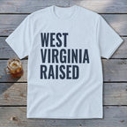 Light blue t-shirt with "WEST VIRGINIA RAISED" in dark blue text.