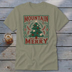 An olive green t-shirt featuring a vintage holiday design with a Christmas tree and the text Mountain Merry.