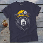 Bear wearing yellow miner's helmet on navy t-shirt with drink beside it.