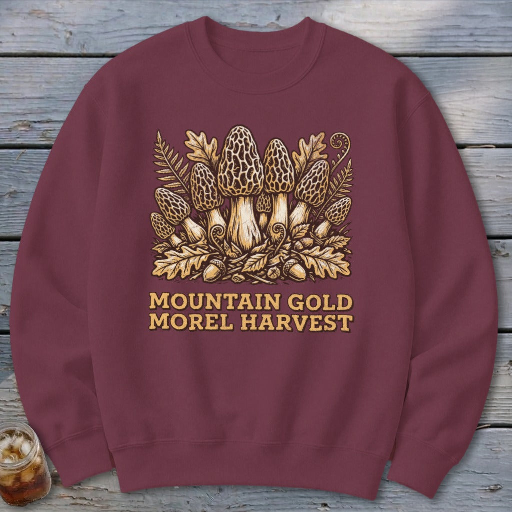 Maroon sweatshirt with a "Mountain Gold Morel Harvest" graphic featuring morel mushrooms and oak leaves.