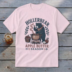 Pink t-shirt with bear making apple butter graphic and text "HOLLERBEAR APPLE BUTTER SEASON".