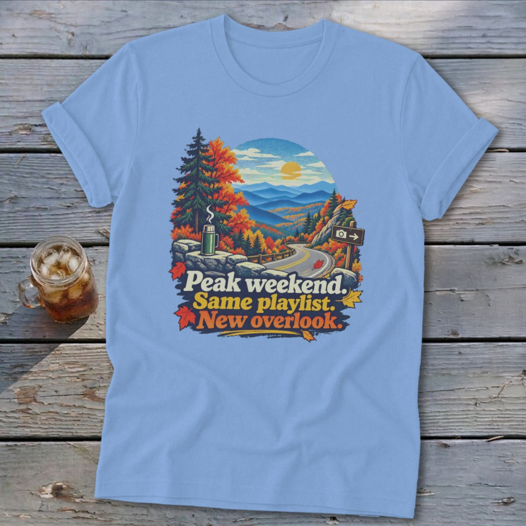 Light blue t-shirt with fall mountain landscape and text "Peak weekend. Same playlist. New overlook."