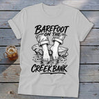 T-shirt with "Barefoot on the Creek Bank" text and graphic of bare feet on rocks in water.