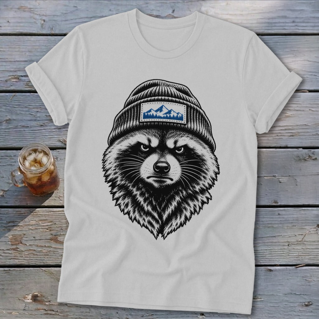 White t-shirt with a black raccoon graphic wearing a beanie with a mountain patch.