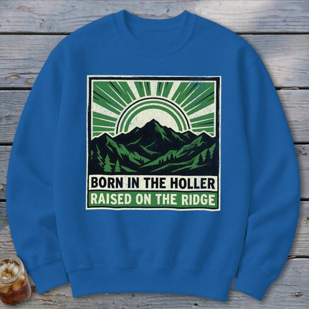 Blue crewneck sweatshirt with a graphic of mountains and text reading Born in the Holler Raised on the Ridge.
