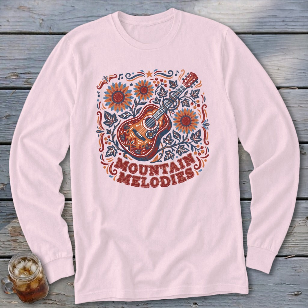 Light pink long-sleeved shirt with a folk art guitar graphic surrounded by sunflowers and the text Mountain Melodies.