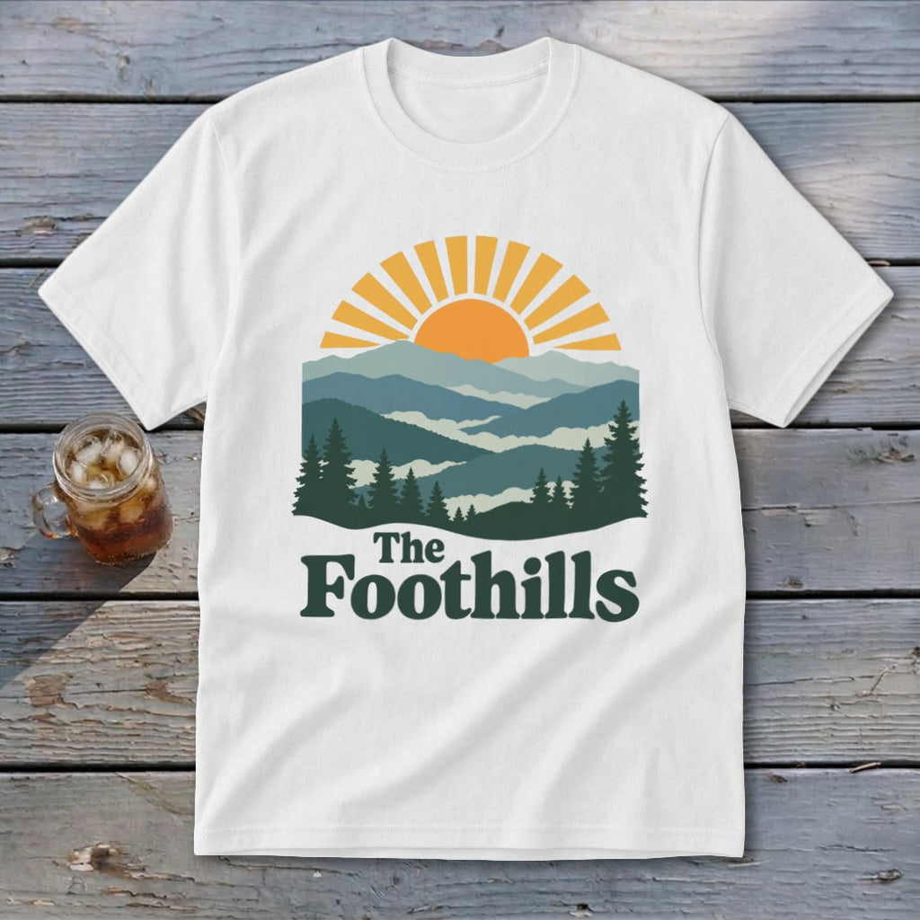 White t-shirt with mountain landscape graphic and text "The Foothills".