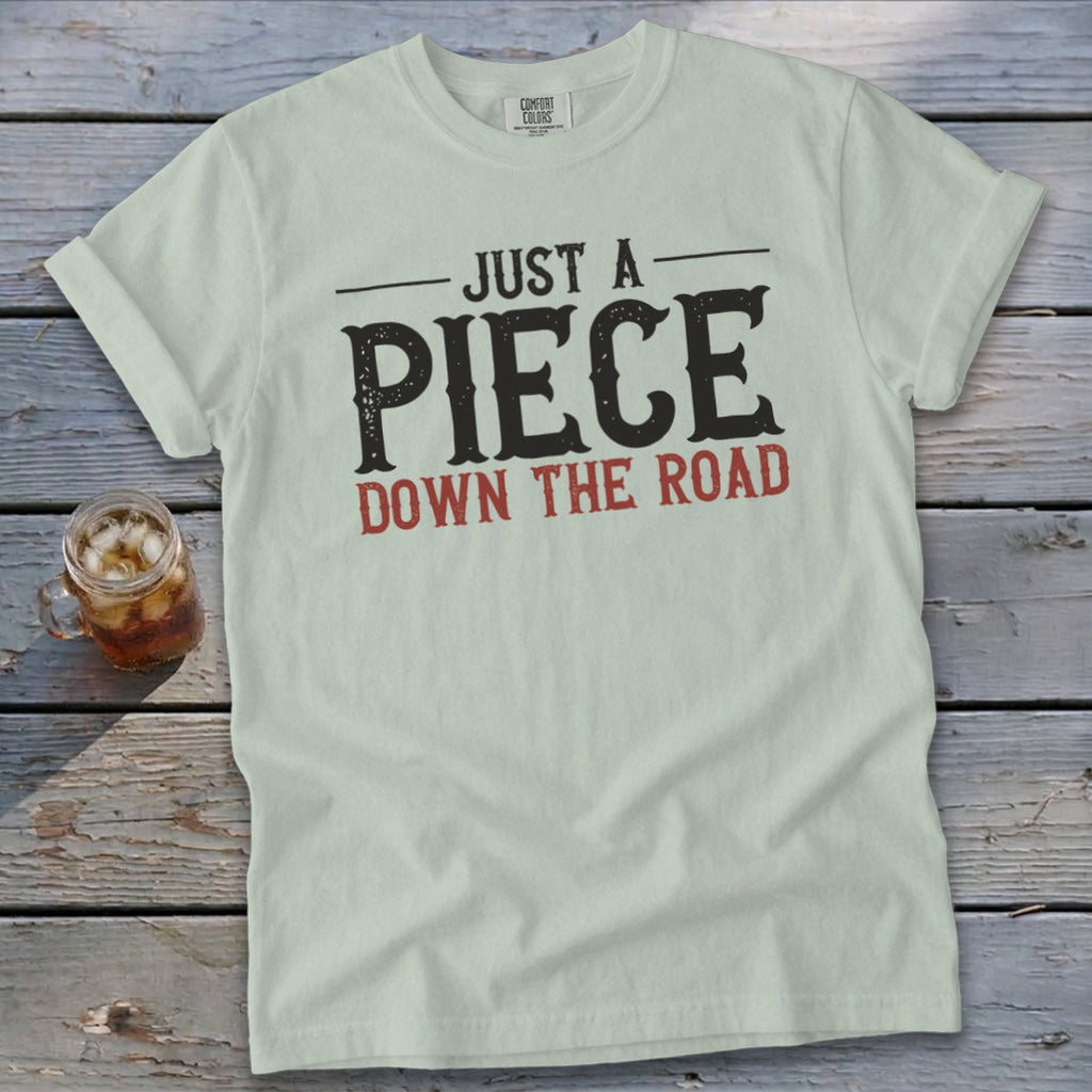 Light green t-shirt with "JUST A PIECE DOWN THE ROAD" graphic.