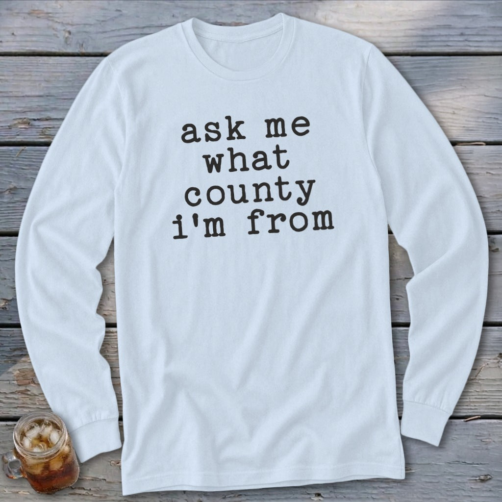 Light blue long-sleeve t-shirt with black text reading "ask me what county i'm from".