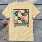 Yellow t-shirt featuring a Drunkard's Path quilt design with text below.