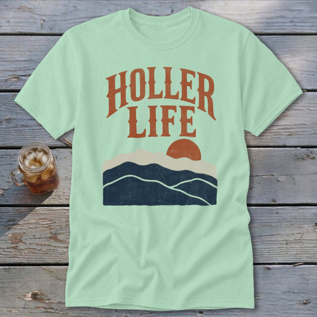 Light green t-shirt with the orange text HOLLER LIFE above a sunset landscape graphic.
