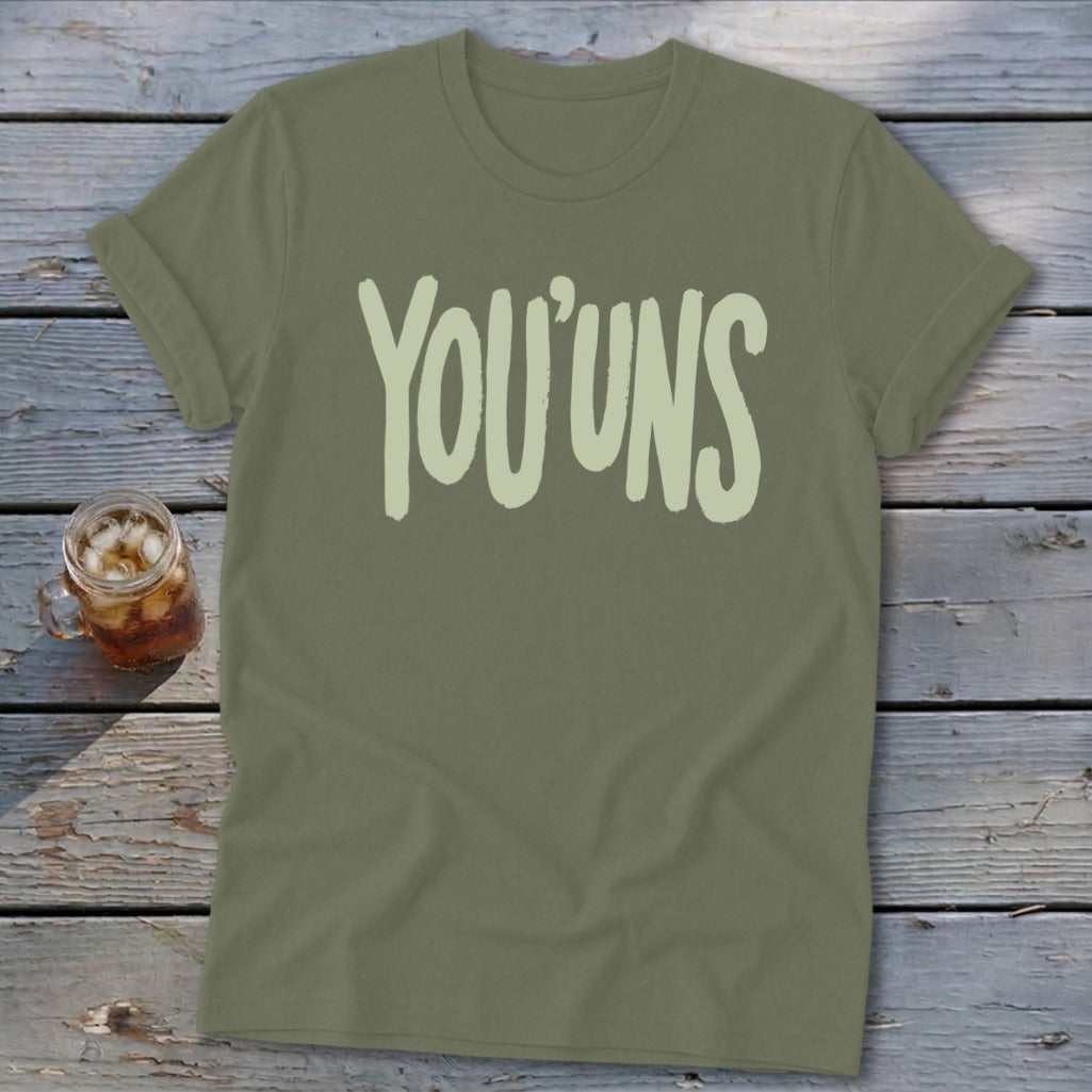 Olive green t-shirt with "YOU'UNS" text in pale green, next to a glass of iced tea.