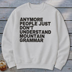 White crewneck sweatshirt with black text: "Anymore People Just Don't Understand Mountain Grammar."