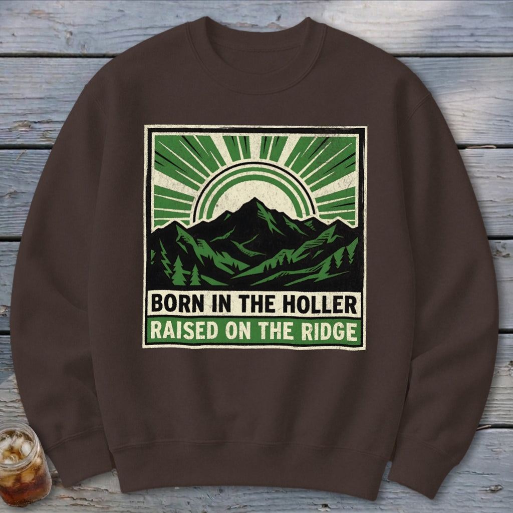 Brown crewneck sweatshirt featuring a graphic of mountains and sunburst with the text BORN IN THE HOLLER RAISED ON THE RIDGE.