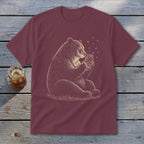 Maroon t-shirt with illustration of a bear holding a jar of fireflies.