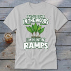 A light gray t-shirt with green text reading "IF YOU SEE ME IN THE WOODS I'M HUNTIN' RAMPS" and an illustration of three ramp plants.