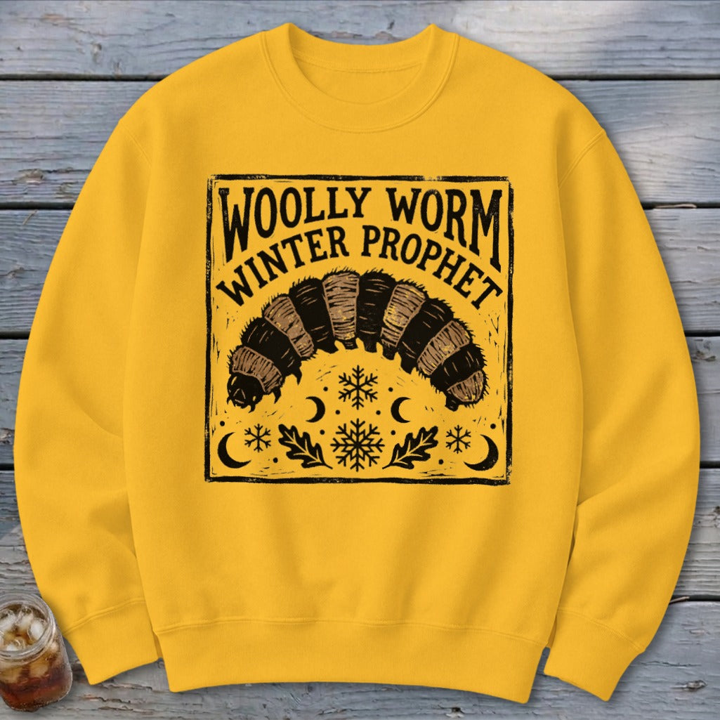 Yellow crewneck sweatshirt featuring a black graphic of a woolly worm, snowflakes, crescents, and text reading Woolly Worm Winter Prophet.
