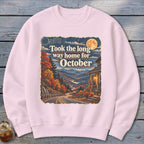 Pink sweatshirt with "Took the long way home for October" text and autumn mountain landscape.