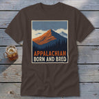 Brown t-shirt featuring a retro mountain graphic with Appalachian born and bred text laid flat on a rustic wooden surface.