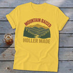 A yellow t-shirt features a vintage mountain graphic with the text Mountain Raised Holler Made.