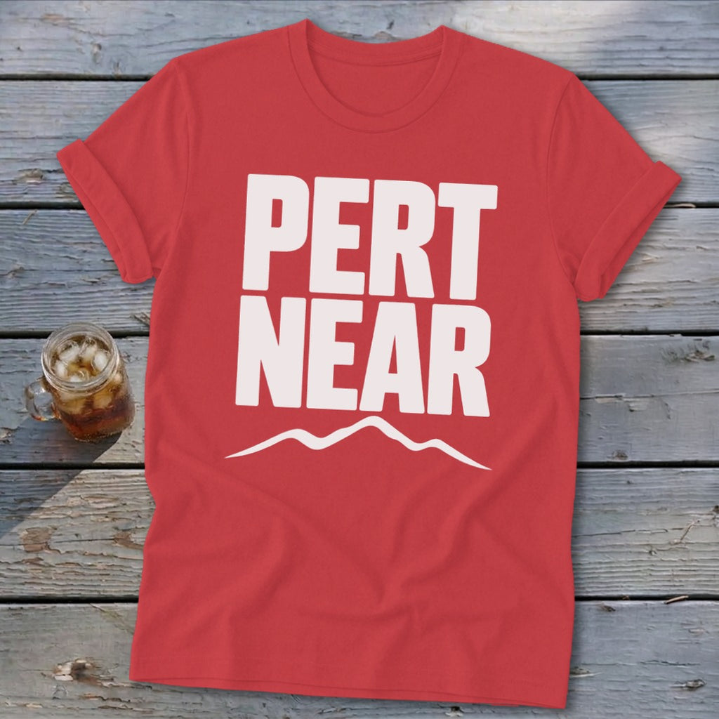 Red short-sleeve t-shirt with white text that reads PERT NEAR above a mountain range graphic.