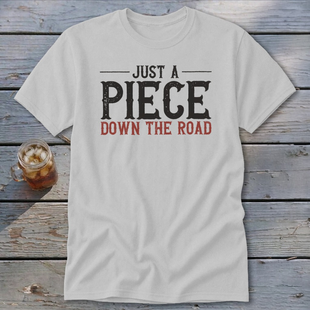 White t-shirt with text "JUST A PIECE DOWN THE ROAD"