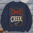 Navy sweatshirt with a distressed sign that says "CRICK" crossed out and "CREEK" with a checkmark.