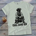 Light gray t-shirt with black graphic of a boy in overalls and cap holding a bucket, text reads "COAL CAMP KID".