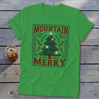 Bright green t-shirt with a vintage Christmas tree graphic and the text Mountain Merry on a rustic wooden background.