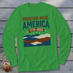 Green long-sleeve shirt with Mountain-Made America 1776-2026 text and wavy mountain graphics.