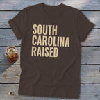 Brown t-shirt with "SOUTH CAROLINA RAISED" text in beige.