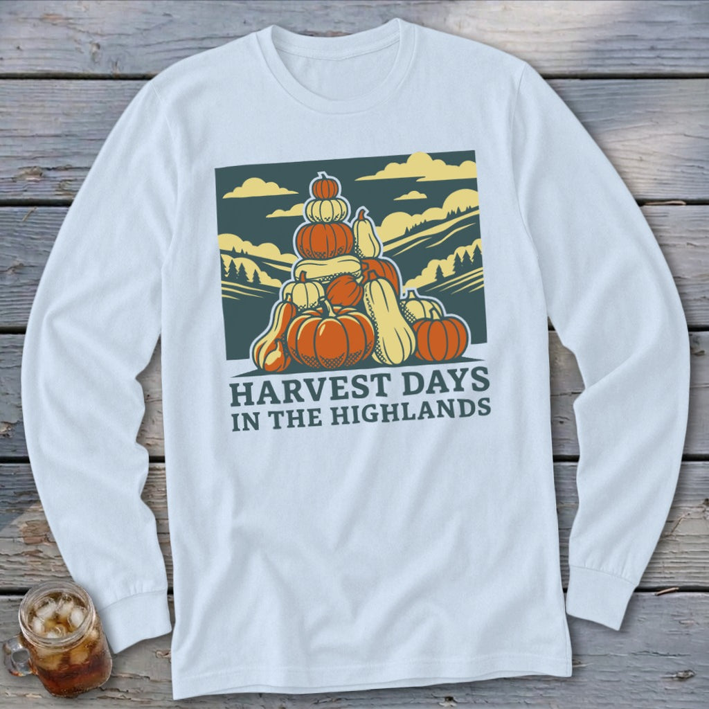 White long-sleeve t-shirt with a graphic of stacked pumpkins, rolling hills, and the text Harvest Days in the Highlands.