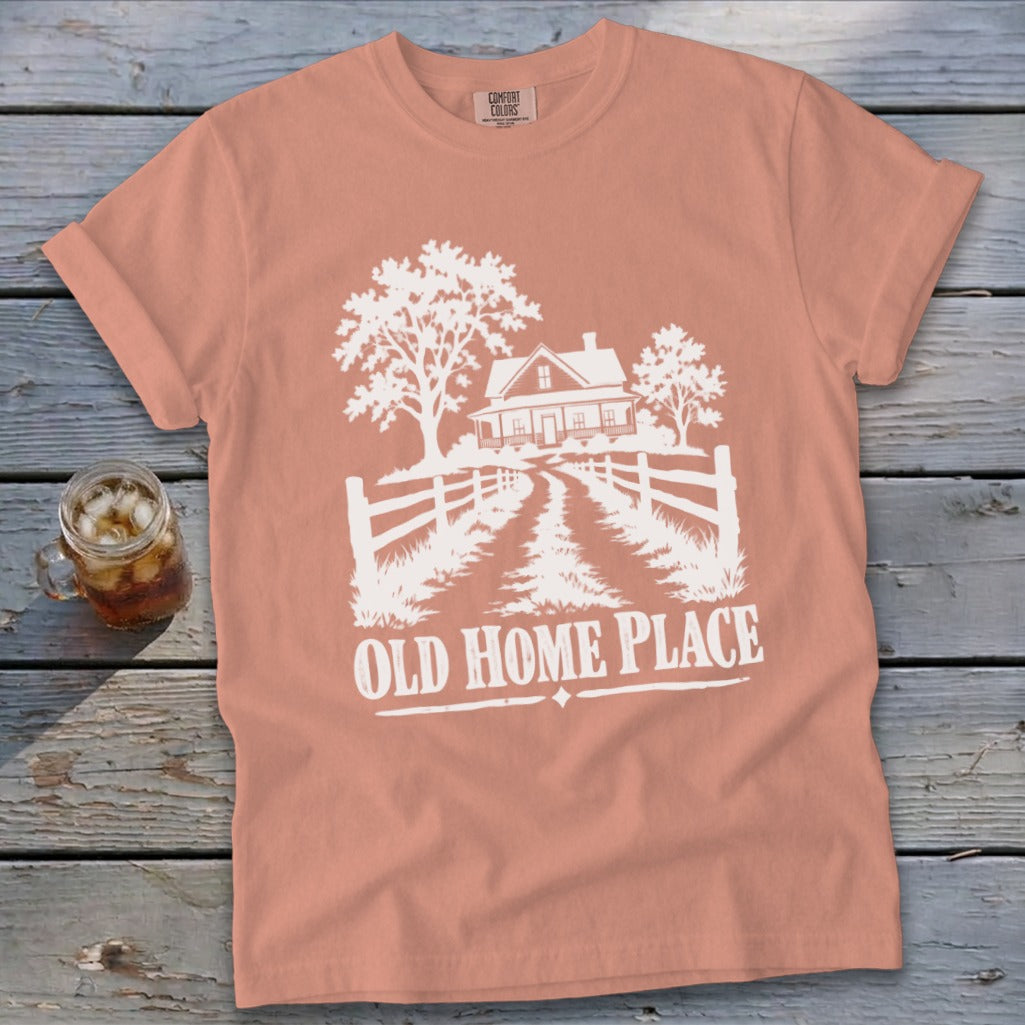 T-shirt with white graphic of a farmhouse, trees, fence, and text "OLD HOME PLACE".
