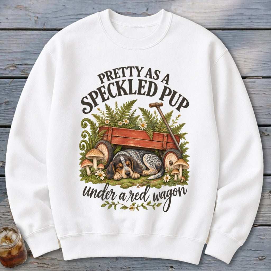 Dog sleeping under a red wagon with text "Pretty as a Speckled Pup".