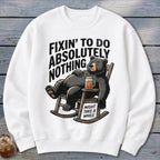 A white crewneck sweatshirt features an illustrated black bear relaxing in a rocking chair with a drink.