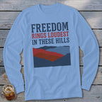 Light blue long-sleeve t-shirt with a graphic of layered hills and the text Freedom Rings Loudest in These Hills.