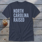 Navy t-shirt with "NORTH CAROLINA RAISED" text in light blue block letters.