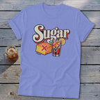 Periwinkle t-shirt with a graphic of cornbread marked with a red X and iced tea with a green checkmark below the text Sugar.
