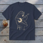 Bear playing a banjo while sitting on a stool on a navy blue t-shirt.