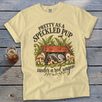 Yellow t-shirt with "Pretty as a Speckled Pup" and a sleeping dog under a red wagon.