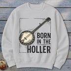 White sweatshirt with a banjo graphic and text "BORN IN THE HOLLER".