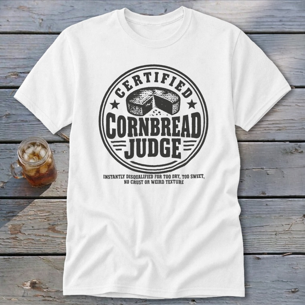 White t-shirt featuring a black graphic that reads Certified Cornbread Judge surrounding a cornbread wheel.