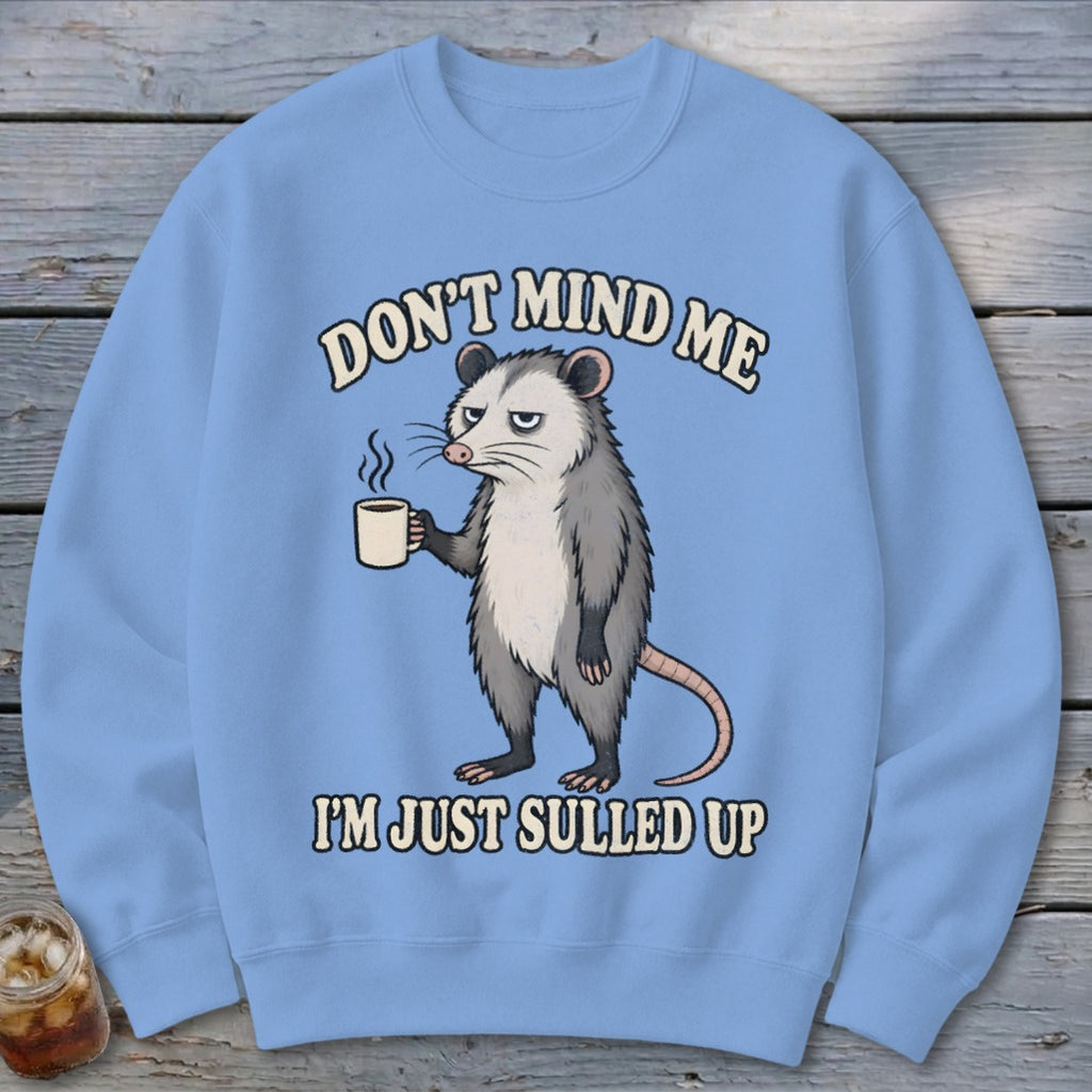 Light blue sweatshirt with an opossum holding coffee and text "Don't mind me, I'm just sulled up."
