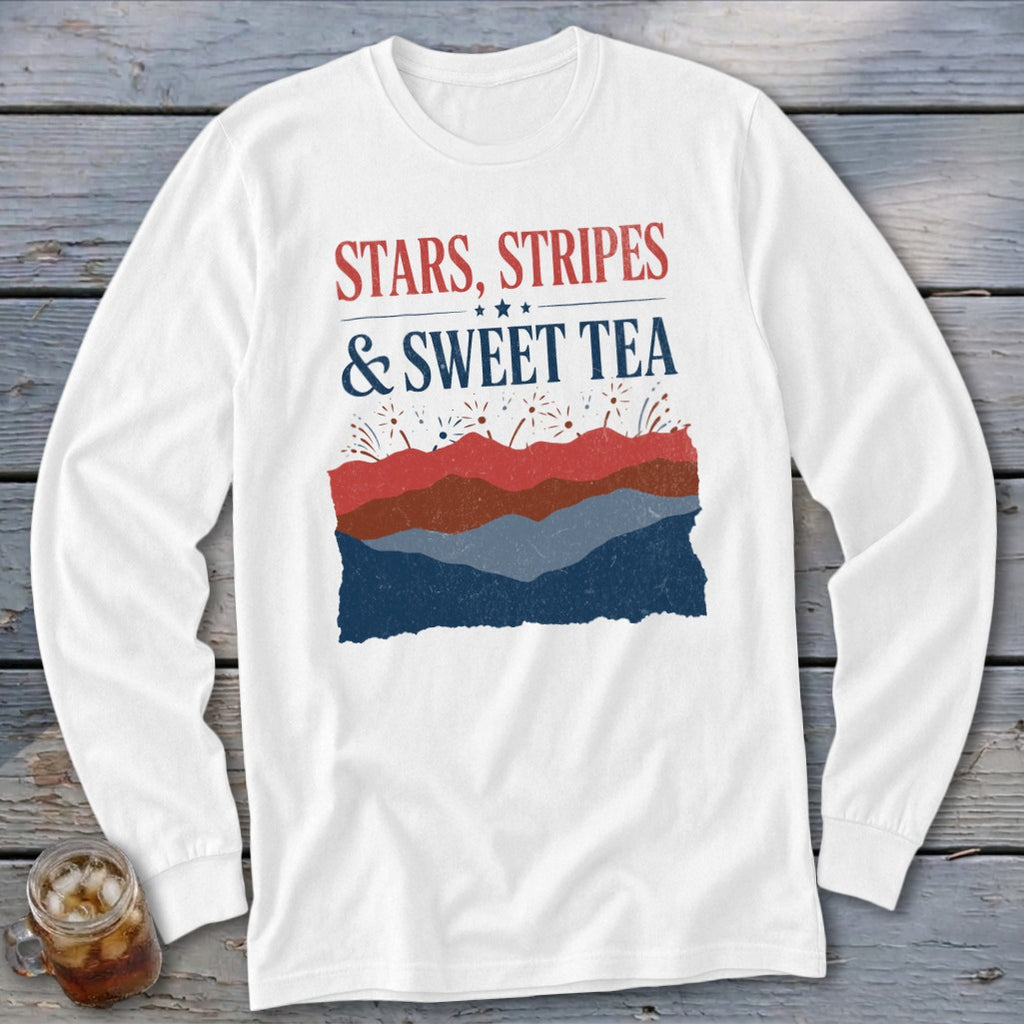 White long-sleeve t-shirt with red and blue text reading STARS STRIPES & SWEET TEA above layered hills and fireworks.