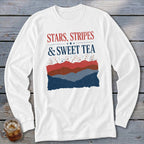 White long-sleeve t-shirt with red and blue text reading STARS STRIPES & SWEET TEA above layered hills and fireworks.