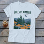 A white t-shirt featuring a green graphic and text reading DOLLY SODS WILDERNESS WEST VIRGINIA HIGHLANDS.